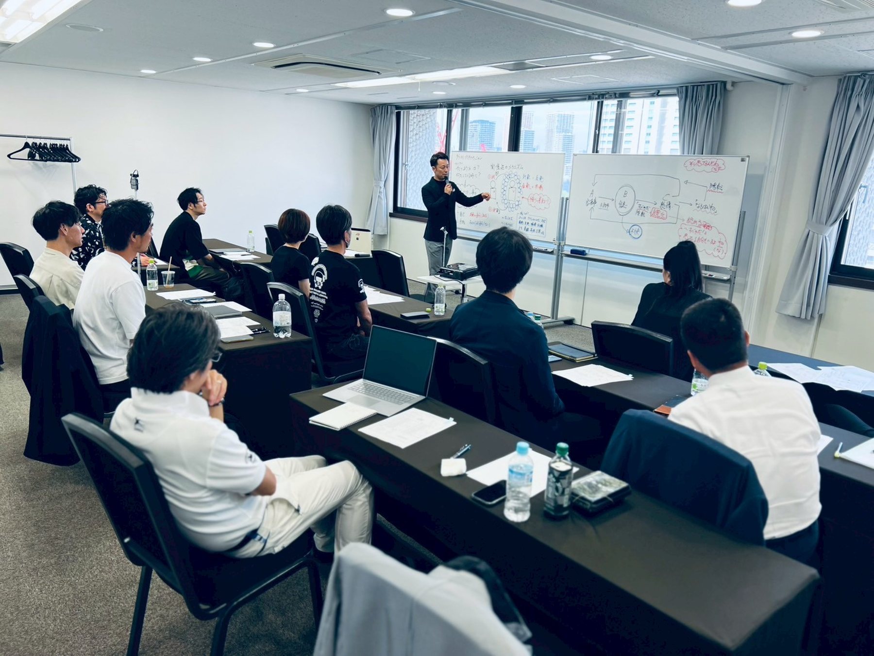 体験会の様子。ホワイトボードの前に立つ村松高志が話し、参加者が着席して聞いている。